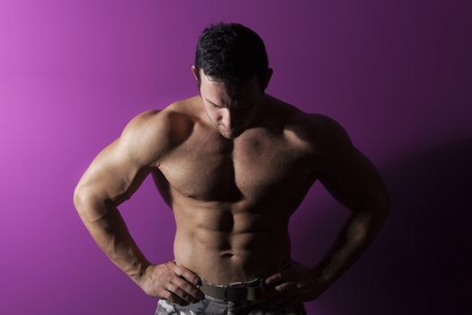 Sexy muscular bodybuilder isolated on purple background. Muscle and fitness fine art portrait.