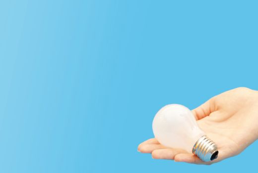 Background with lit lightbulb. Isolated on blue