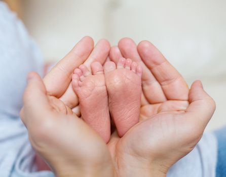 Leg of the newborn in the hands of father