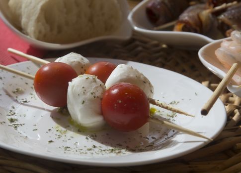 Tapas plate with tomatoes, mozzarella cheese, olive oil and herbs