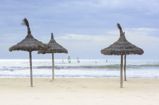 Windsurfers and parasols in Playa de Palma, November. Mallorca, Balearic islands, Spain.