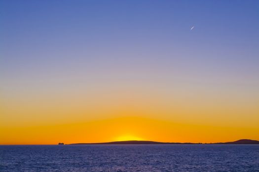 Colorful Sunset Traffic. Sunset view in blue and yellow with airplane and ferry traffic. Palma bay, Mallorca, Balearic islands, Spain.