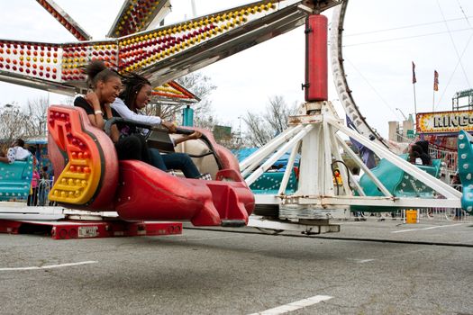 Atlanta, GA, USA - March 15, 2014:  Two teens enjoy riding a fast-moving carnival ride at the annual Atlanta Fair.