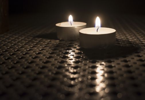 Two Tealights on outdoor table in the dark.