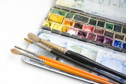 Watercolor box. Artist tools - a well used and messy watercolor box and brushes.