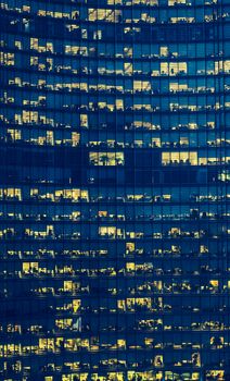 High Rise Office Building with many floors and visible but anonymous people at dusk.