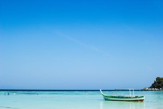 Beautiful small fishing wooden boat located in blue sea and sky