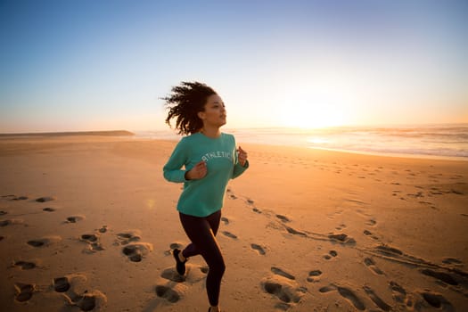 Young afro woman running on the beach