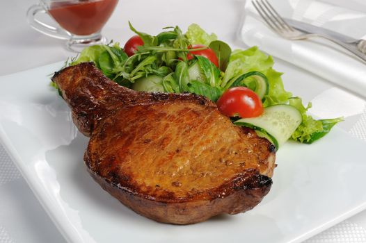 Fried steak on the bone with vegetables and ketchup