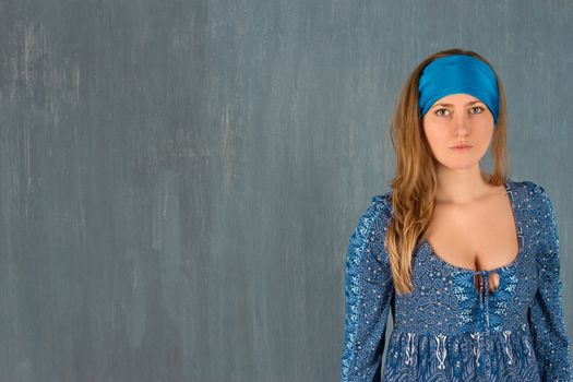 Girl in blue dress on wall background