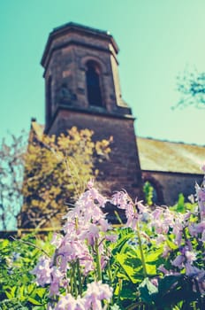 Retro Filtered Photo Of A Rural Church Steeple With Flowers In The Foreground