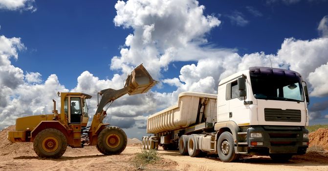 Front end loader placing stone and sand into a large truck or trailer