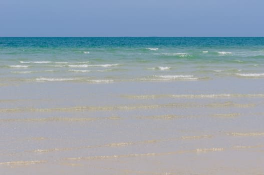 Sea with waves sandy coastline and deep blue sky