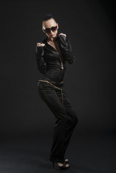 Full length shot of beautiful Caucasian woman wearing black bodysuit and dancing, against black background