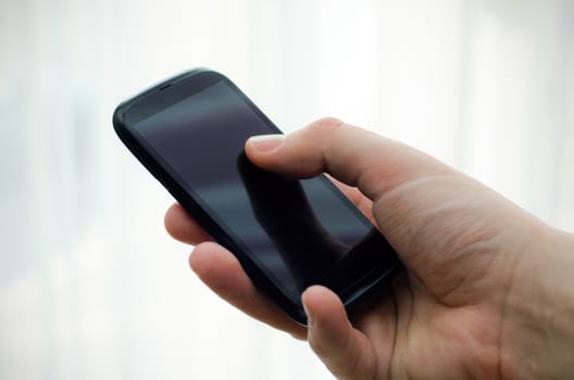 Hand holding mobile phone with blank display