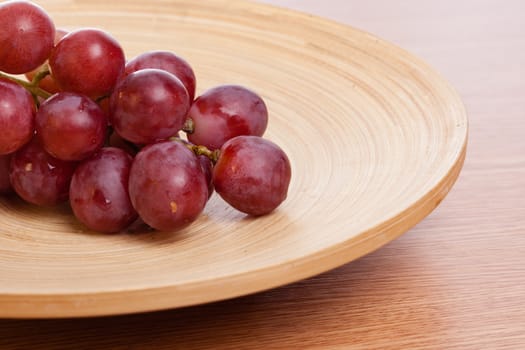 Big rose grapes on a wooden plate