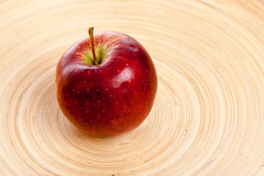 big red apple in middle of a wooden plate