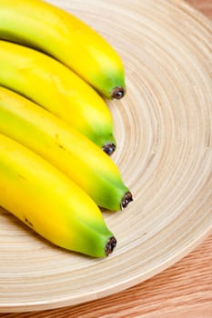 fresh yellow banana on brown wooden plate