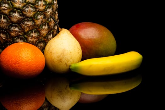 bunch of exotic fruits on black background with reflection