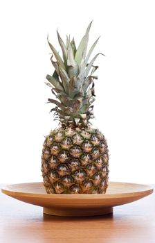 Big pineapple on a wooden plate with white background
