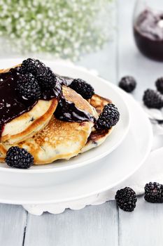 Delicious golden pancakes with fresh blackberries and blackberry jam. Extreme shallow depth of field.