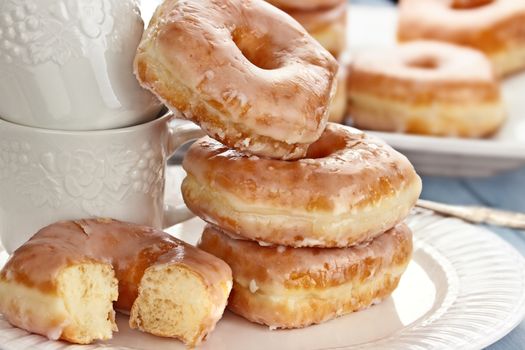 Stack of coffee cups and delicious glazed donuts.