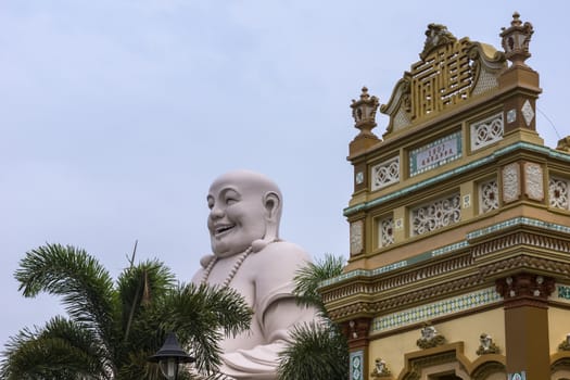 At the Vinh Tranh Pagoda in My Tho, the Mekong Delta, stands this huge statue of the smiling Buddha. Here, the head of the Buddha is seen in combination with the top of one entrance to the Pagoda.