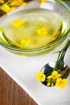 Rapeseed oil with rapeseed blossoms on table background