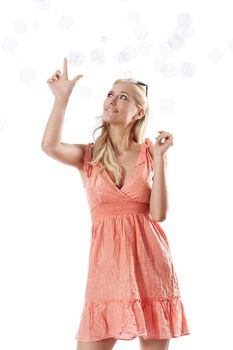 pretty young blond woman wearing a summer orange dress standing against white background playing with some soap bubbles