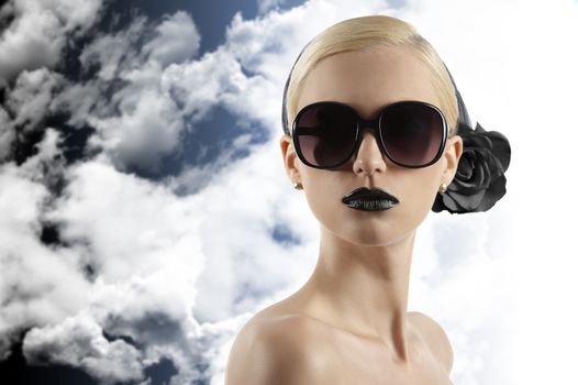 fashion portrait of young blond woman with hair style black lips and wearing sunglasses looking at the camera against white background
