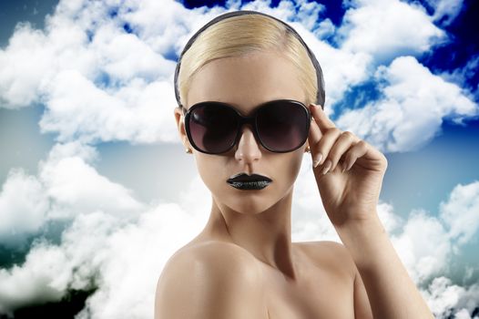fashion portrait of young blond woman with hair style black lips and wearing sunglasses looking at the camera against white background