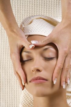 Closeup of human hands doing massage a young cute woman face