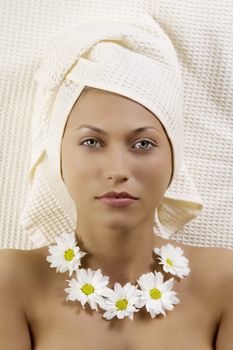 pretty young woman with bath towel and flowers as necklace laying down