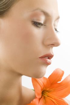 close up of a blond girl with an orange lily near the face