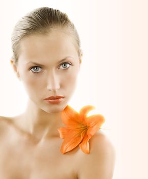 great portrait of a blond girl with wet hair and an orange lily on her shoulder
