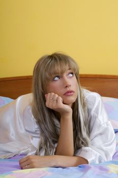 cute blond woman in nightgown sitting on bed with colored sheet