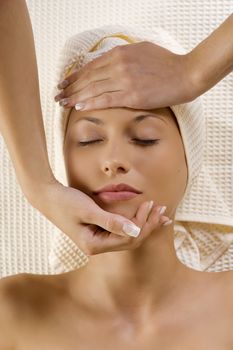 human hands stretching a head of a cute woman in a spa