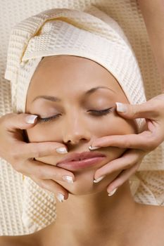 hands massage stretching a beautiful face of a young woman in a spa