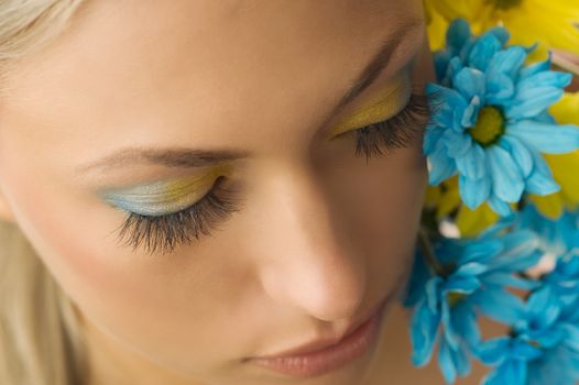 nice beauty portrait of pretty blond girl with blue and yellow daisy and colored makeup