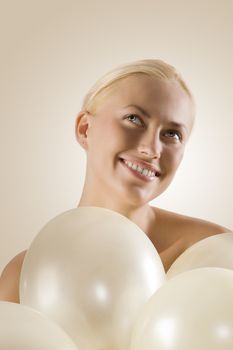close up portrait of a beautiful blond woman with white balloons looking up