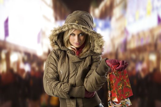 attractive blond woman with shopping bag covering her head with hood from winter