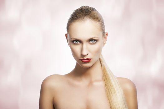 blond pretty woman in a beauty portrait with wet hair and a straight tail over shoulder. She looks in to the lens, the tail is over the left shoulder