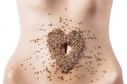 some barley placed in the shape of the heart around the navel, some grains are scattered on the skin.