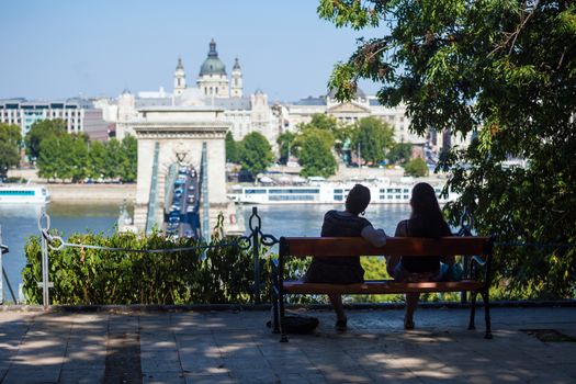 BUDAPEST, HUNGARY - AUGUST 2: Two girls on a bench watching at Szechenyi Chain Bridge on August 2, 2013 in Budapest.