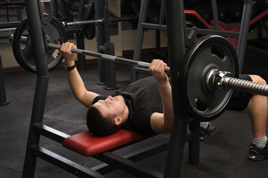 handsome young man doing bench press workout in gym