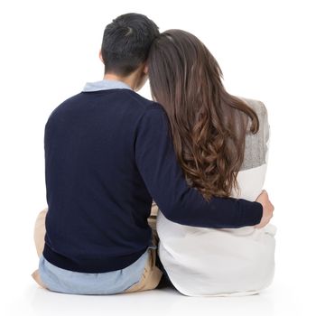 Young couple sitting on ground and hugging, full length portrait isolated on white background.