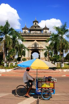 Street food seller on a bicycle in front of Victory Gate Patuxai, Vientiane, Laos, Southeast Asia