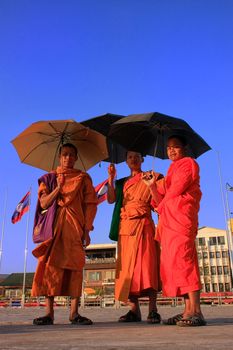 Monks with umbrellas walking near Mekong river, Vientiane, Laos, Southeast Asia
