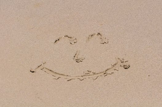 Drawing a smiley face on the sand.