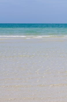 Sea with waves sandy coastline and deep blue sky